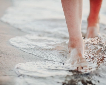Füße, die den Wellensaum an der Ostsee entlanglaufen